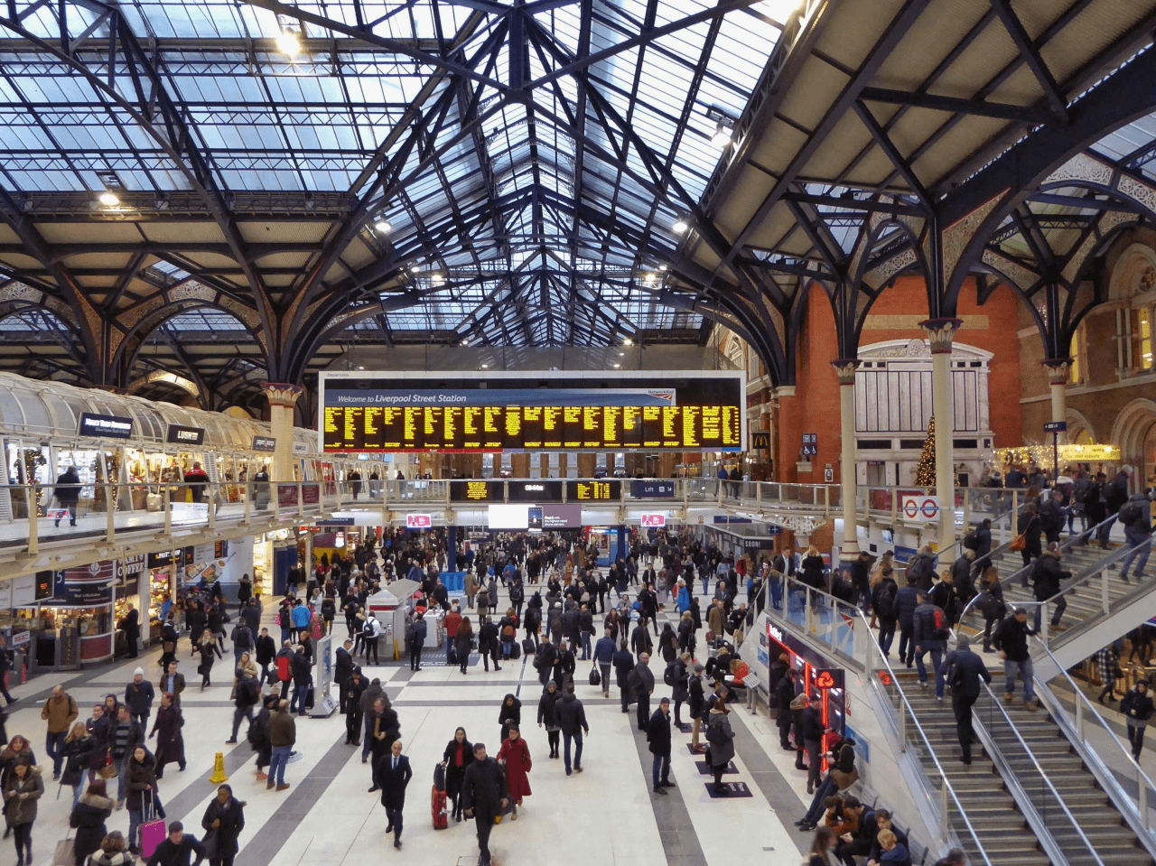 Utasok a londoni Liverpool Street pályaudvar csarnokában az indulási tábla alatt – nyaralás tervezése